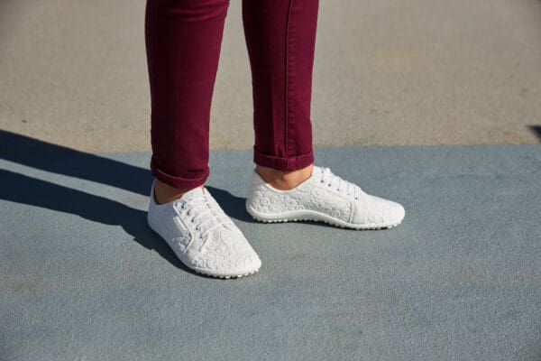 A person standing on the ground wearing white shoes.