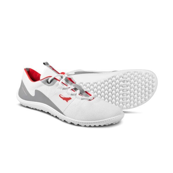 A pair of white shoes with red and grey accents.